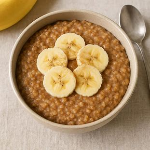 Tigela de mingau de banana com canela e rodelas de banana fresca por cima.