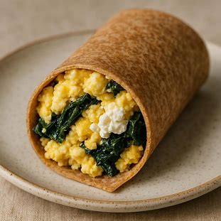 Wrap Integral de Ovos e Ricota. Foto de um wrap ou tortilha integral enrolada, com o interior visível. O recheio é farto, com ovos mexidos, ricota e folhas verdes escuras.