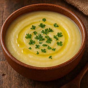 Tigela de creme de mandioquinha com salsinha e fio de azeite, servida quente em prato rústico.