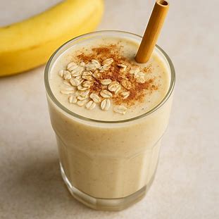 Copo de vitamina de banana com aveia e canela polvilhada, servido com canudo de bambu.