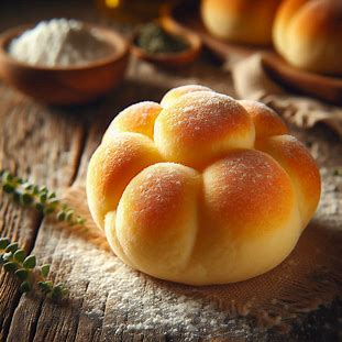 Pão de batata pequeno e dourado, com aparência fofinha e brilho suave.