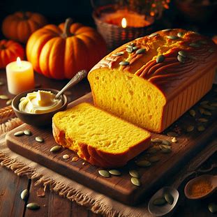 Pão dourado de abóbora com interior amarelo vibrante, fatiado sobre tábua rústica.